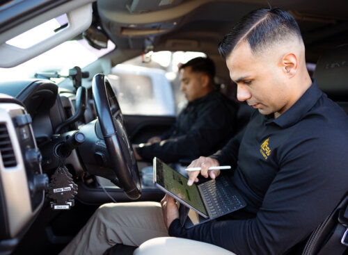 two workers sitting in a truck working on tablets