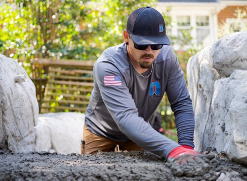 landscaper smoothing out concrete in backyard