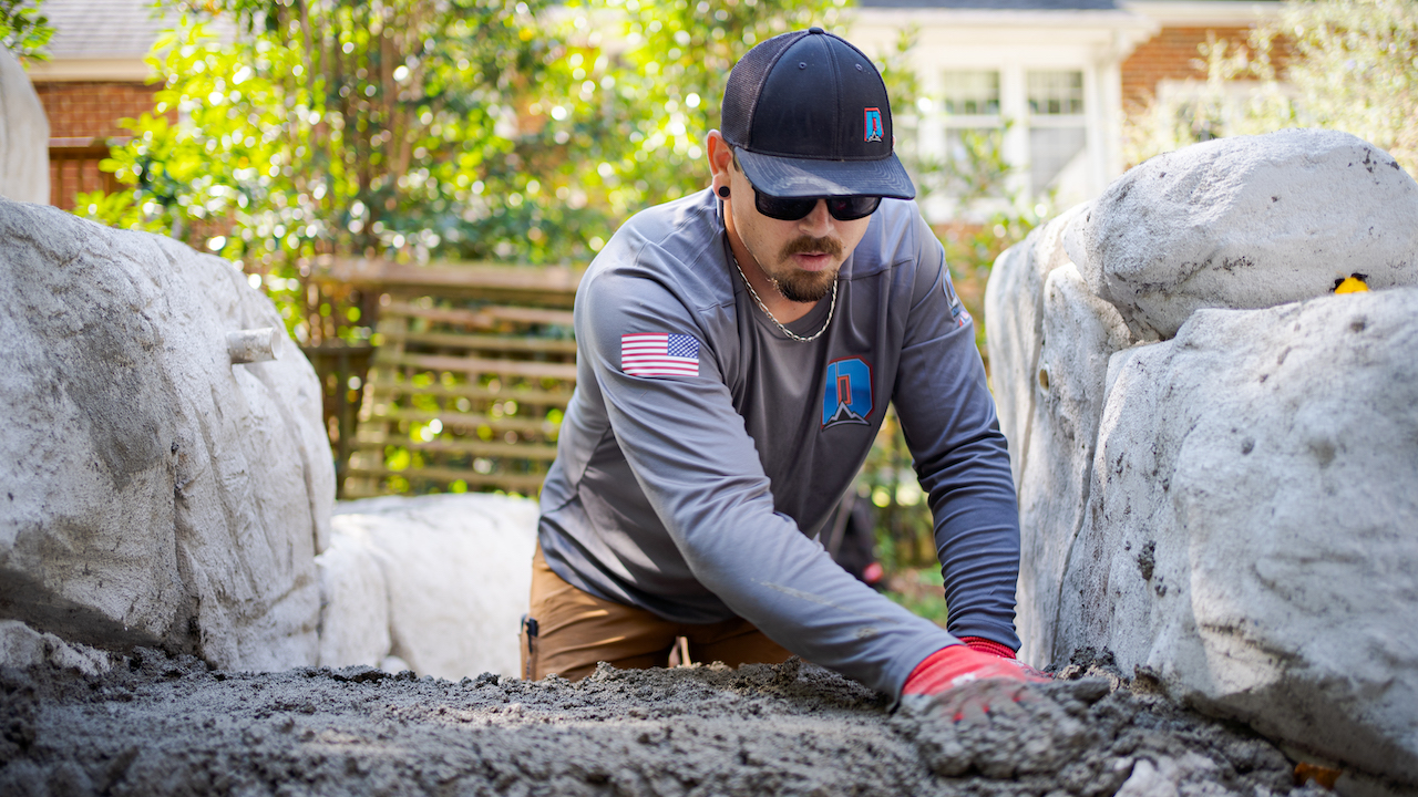 landscaper smoothing out concrete in backyard