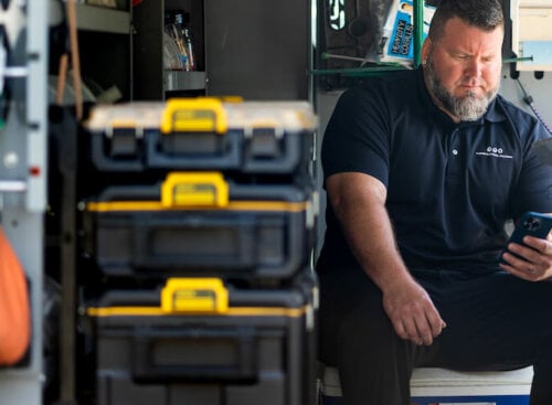 image of electrician sitting in work van looking at his phone