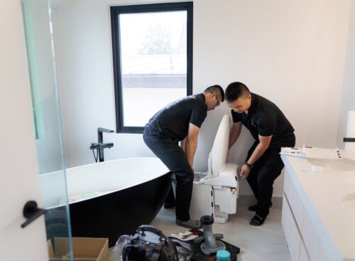 two plumbers working to install a toilet