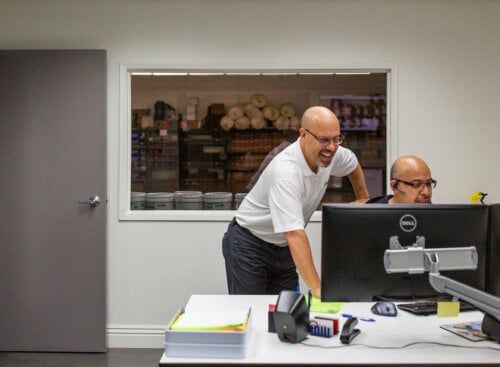 two service workers in an office looking at a computer screen