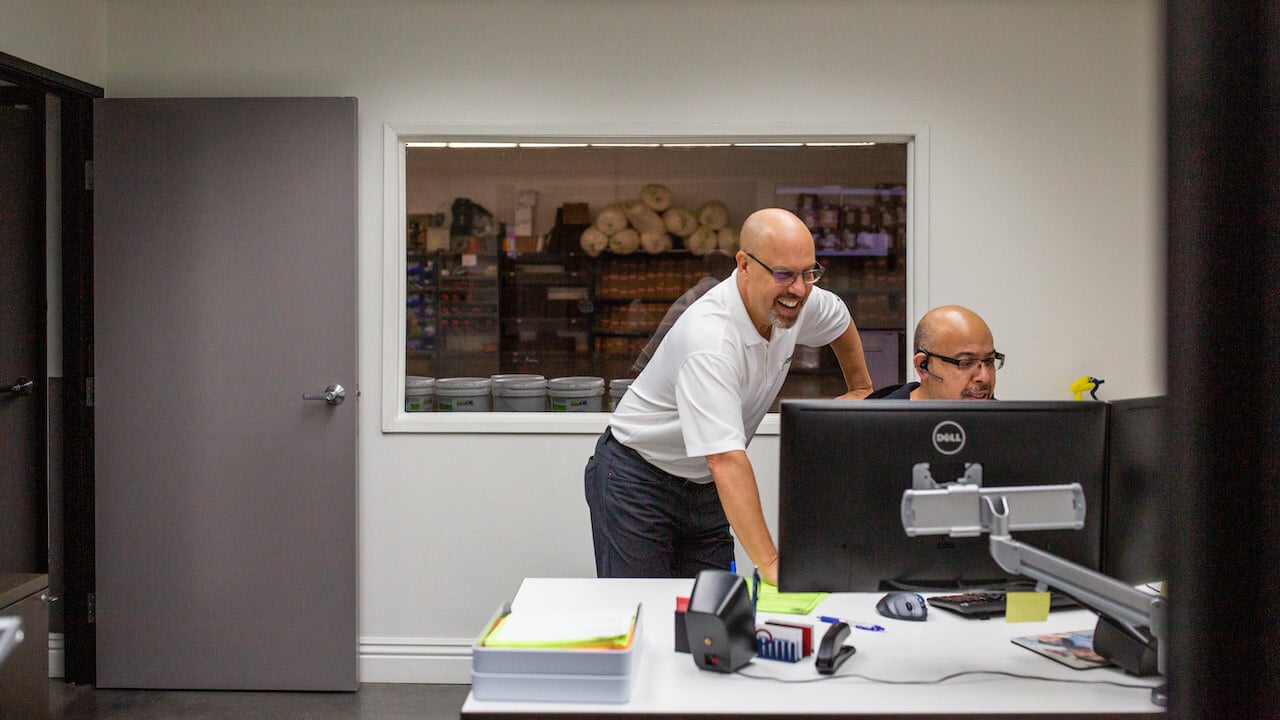 two service workers in an office looking at a computer screen