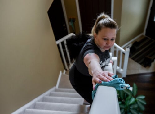 woman cleaning banister in home's front hall