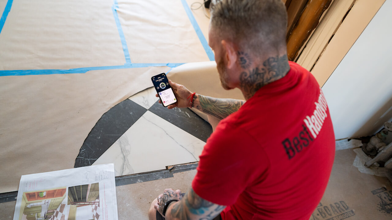 Photo of a handyman business owner using handyman apps on the jobsite