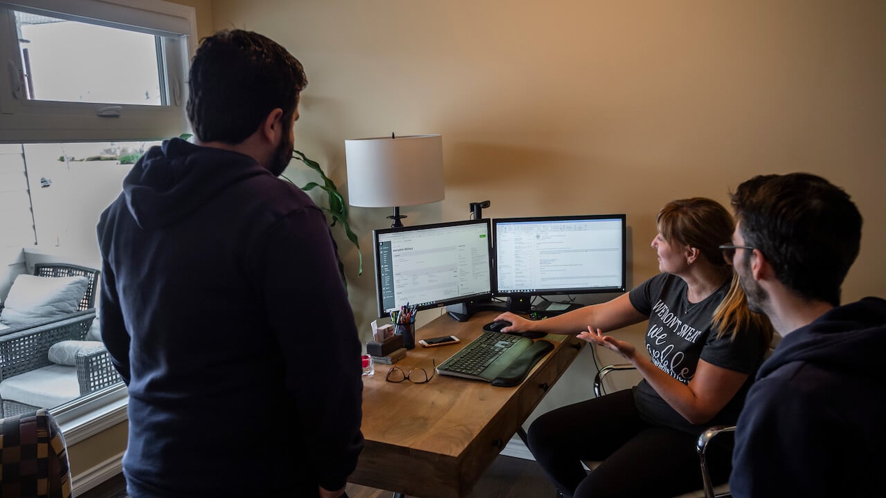 Photo of three home service workers gathered around a computer to write an SOP (Standard Operating Procedure)