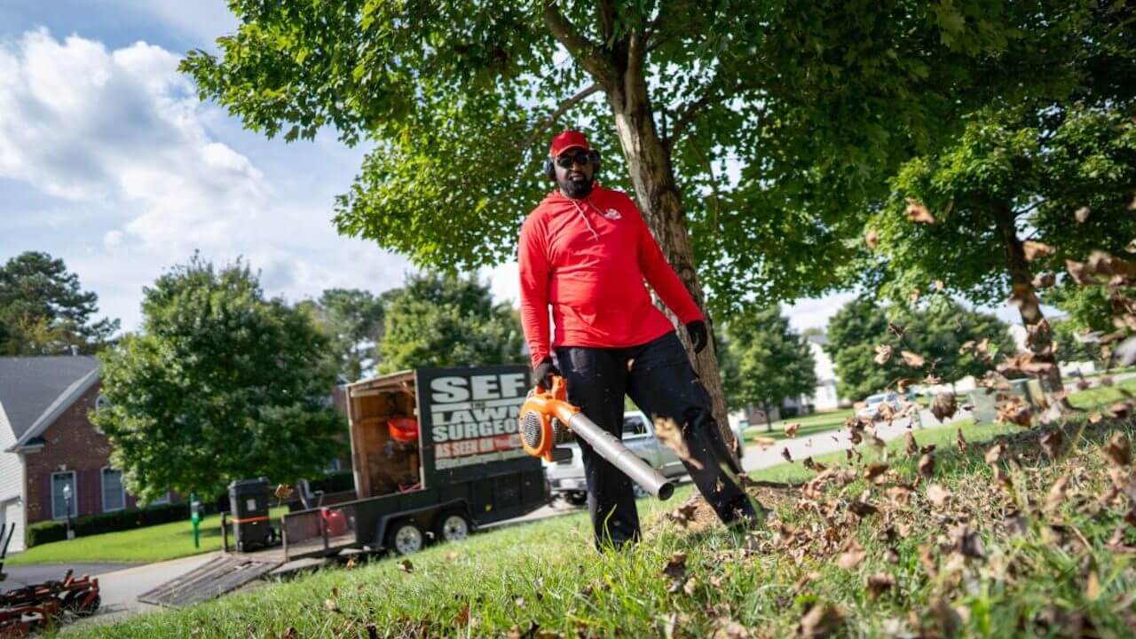 Photo of a lawn care contractor blowing leaves on a client's property