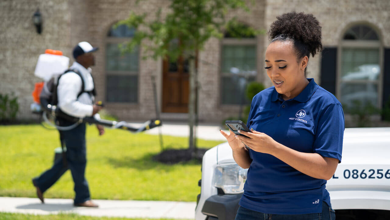 Photo of a small business owner calculating profit margins on her smartphone outside a client's house
