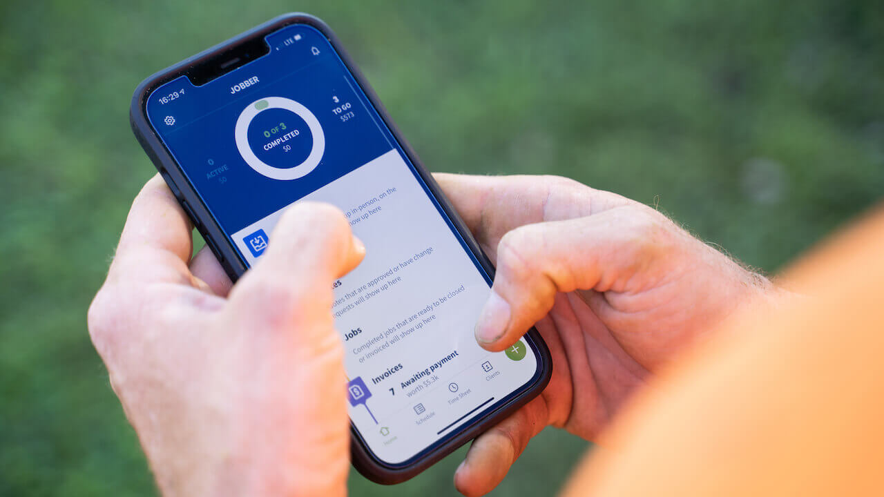 Photo of a business owner using Jobber app to improve cash flow