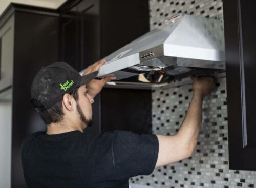 image of service provider repairing over hood vent on stove