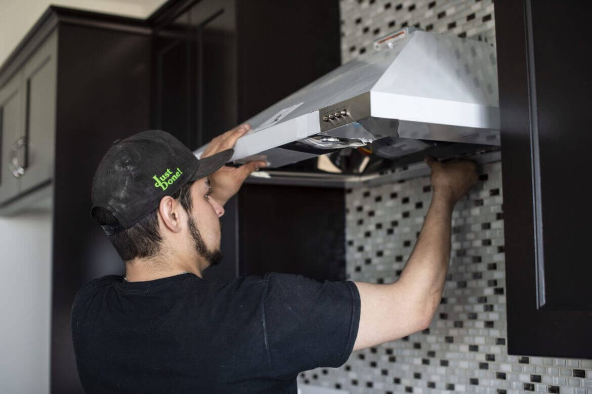 image of service provider repairing over hood vent on stove