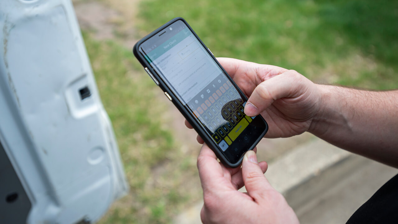 worker holding cell phone while standing outside