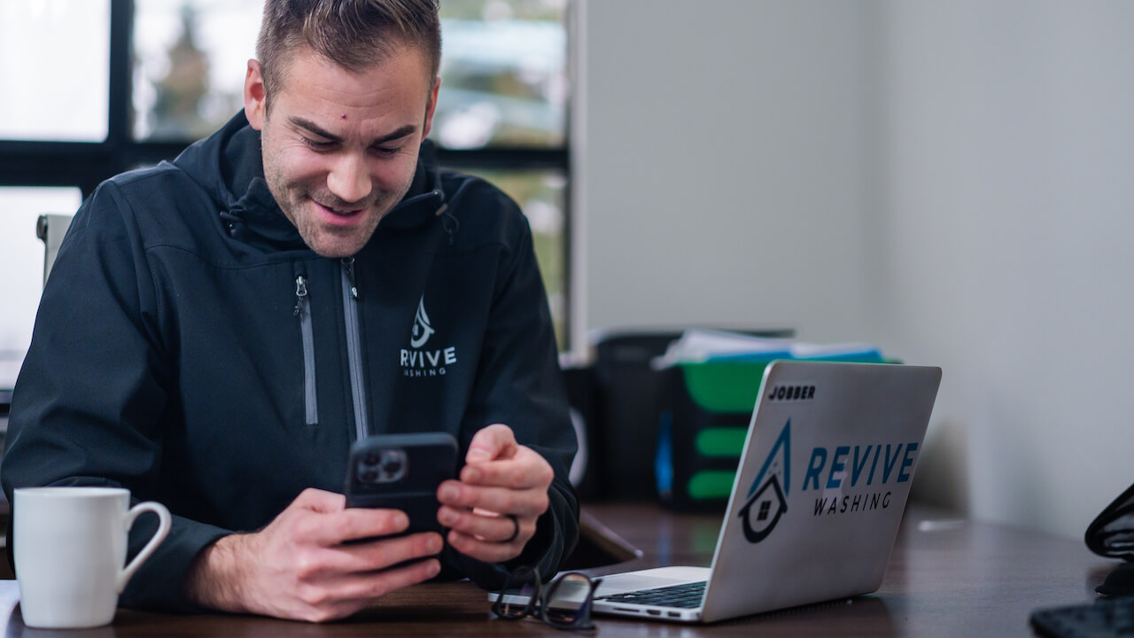 man sitting at desk with phone and laptop