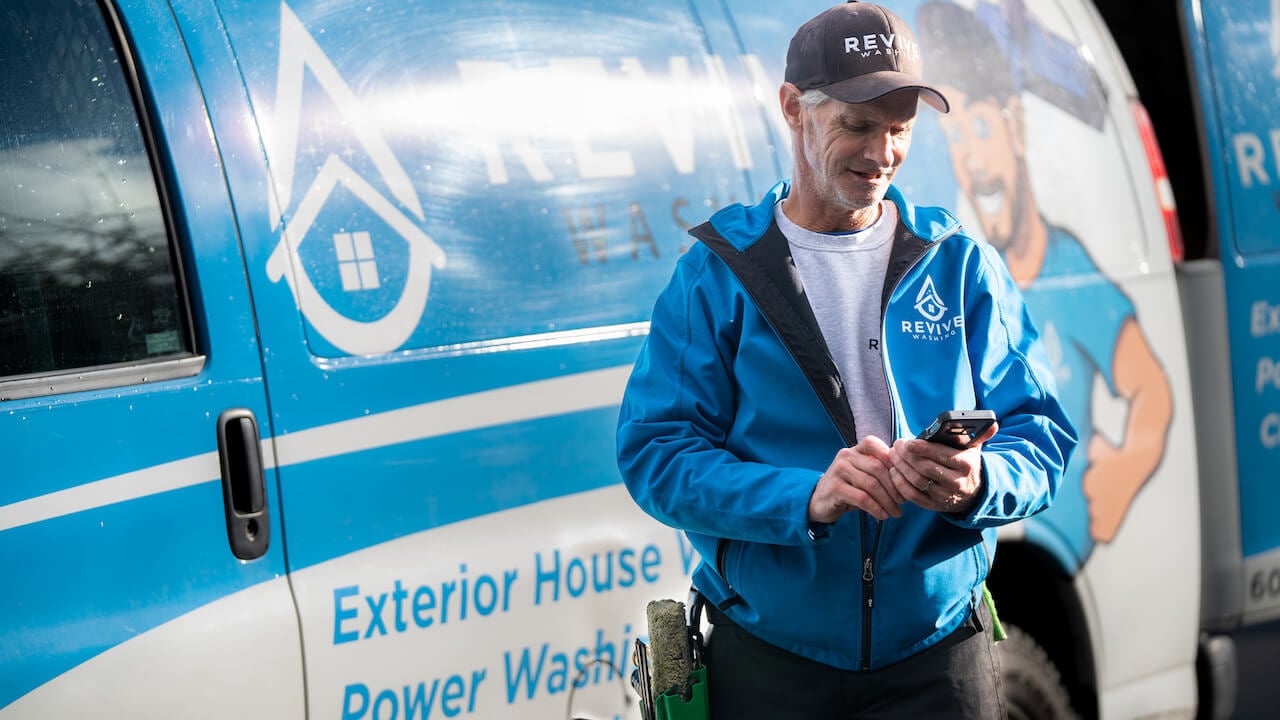 man holding phone standing near company van