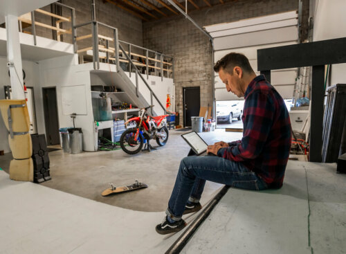 man sitting inside industrial workspace working on laptop
