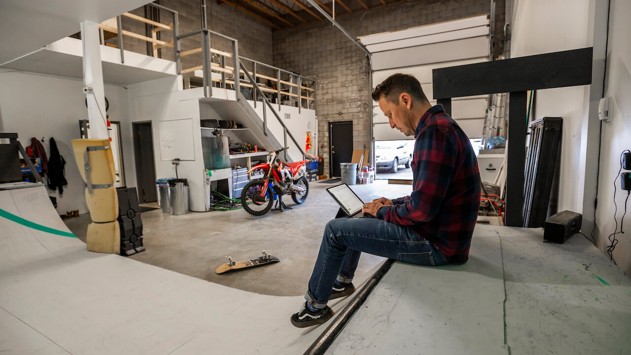 man sitting inside industrial workspace working on laptop