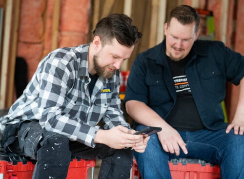 two workers sitting together looking at a phone