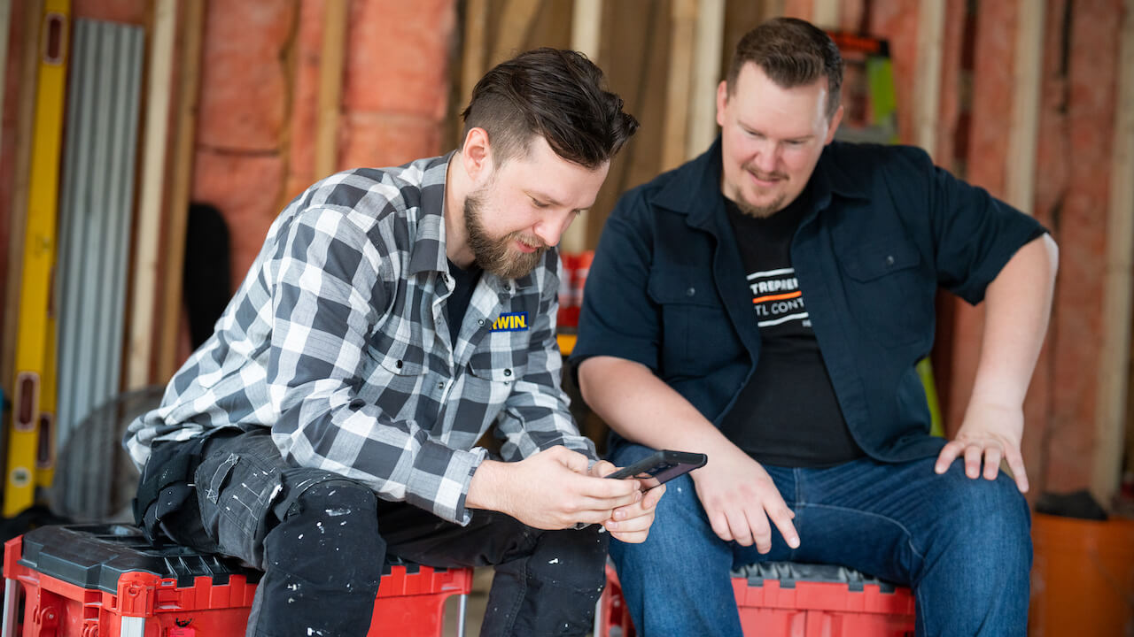 two workers sitting together looking at a phone