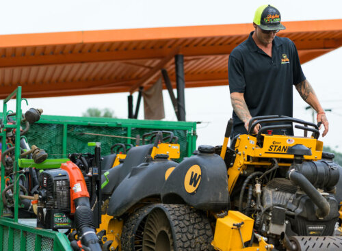 Lawn care worker unloading heavy equipment from trailer