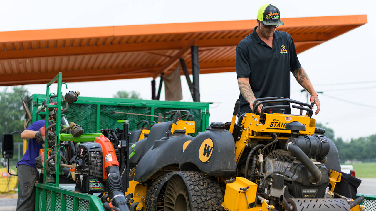 Lawn care worker unloading heavy equipment from trailer
