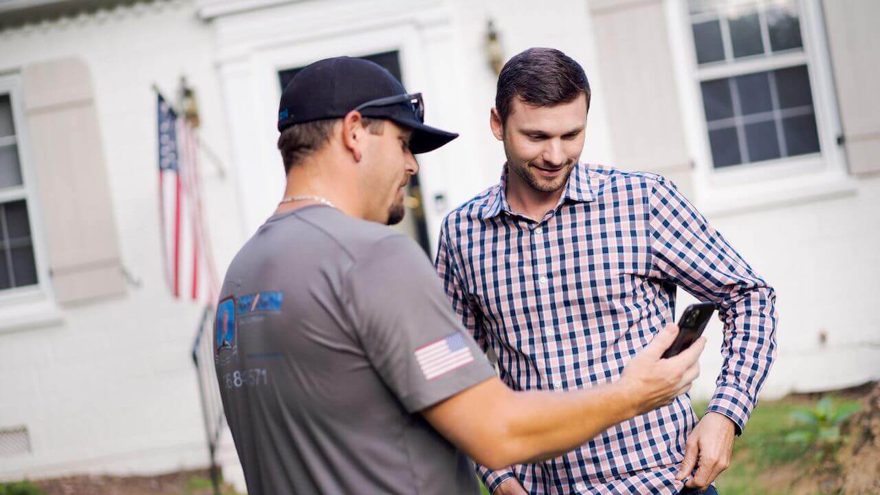 Photo of a home service contractor showing a customer pricing options on his smartphone