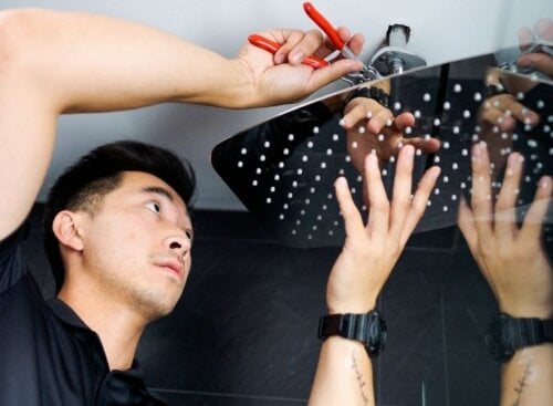 Plumbing service provider installing a shower head with tools