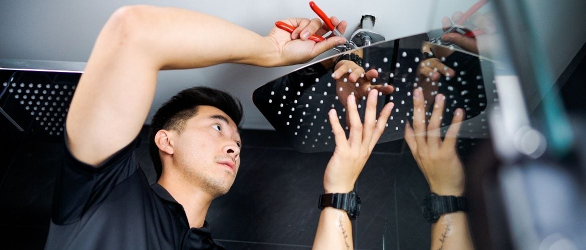Plumbing service provider installing a shower head with tools