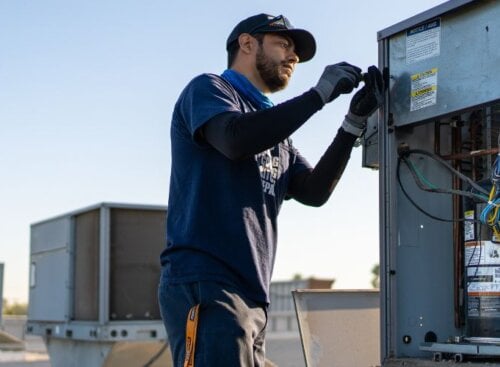 HVAC technician servicing an HVAC system on top of a roof