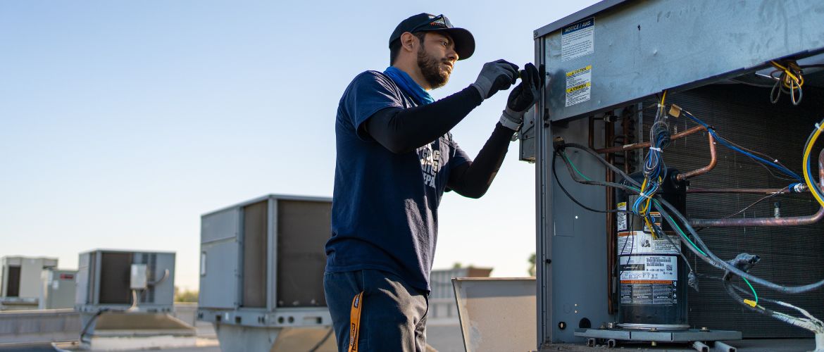 HVAC technician servicing an HVAC system on top of a roof