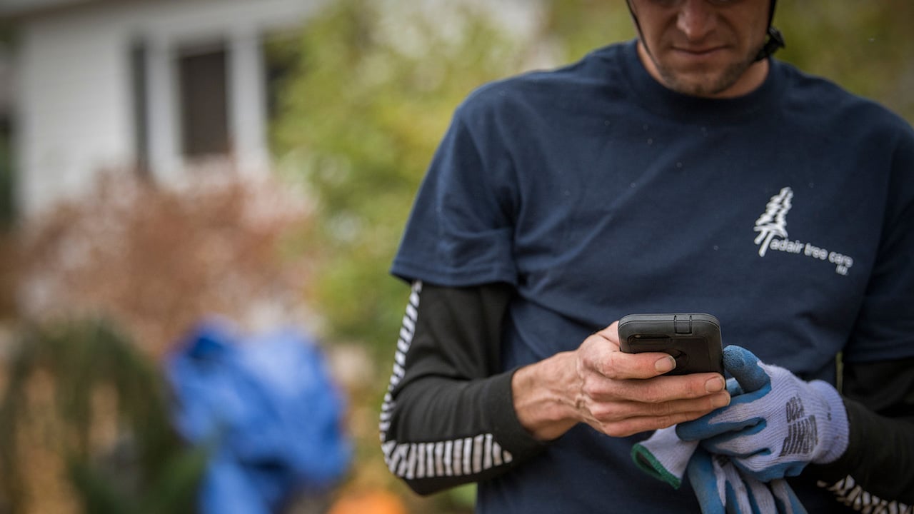 worker holding phone while standing outside