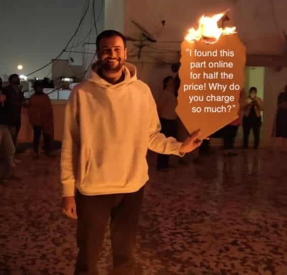 Man smiling and holding a burning piece of paper that says “I found this part online for half the price! Why do you charge so much?”