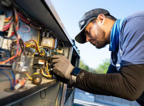Photo of a contractor fixing an HVAC system and duties listed on his HVAC technician job description