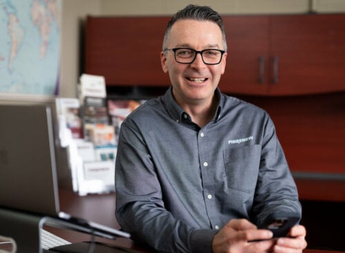 man sitting at desk, smiling at the camera