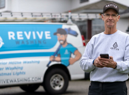 man standing in front of van with pressure washing business name on the side