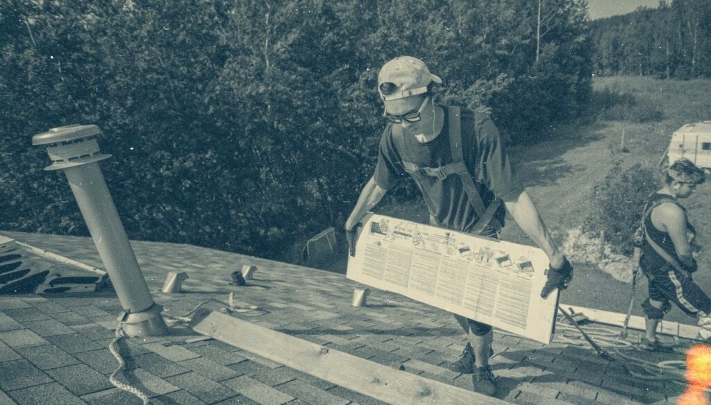 image of roofer working on top of a house