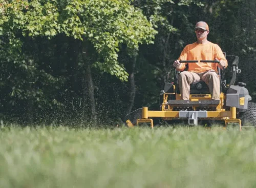 Lawn care professional mowing a lawn after using lawn care business software