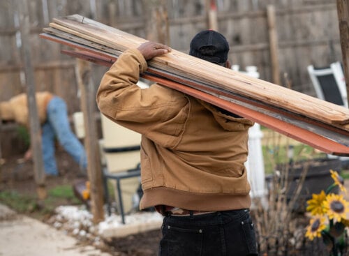 man carrying fence boards