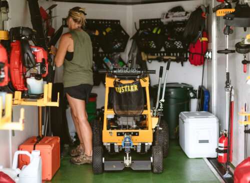 woman standing in work trailer surrounded by tools for landscaping