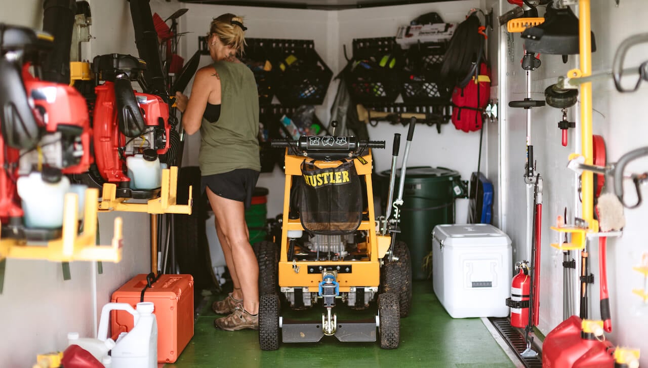 woman standing in work trailer surrounded by tools for landscaping