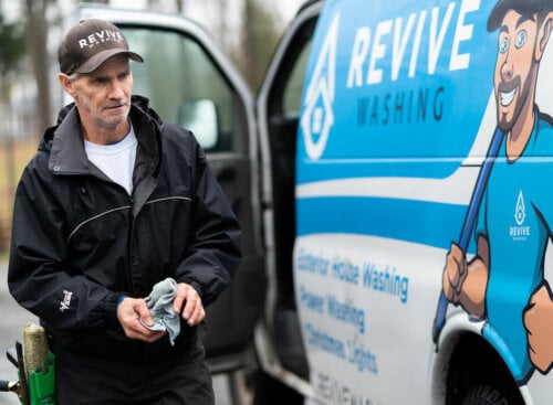 man standing next to a window cleaning company vehicle