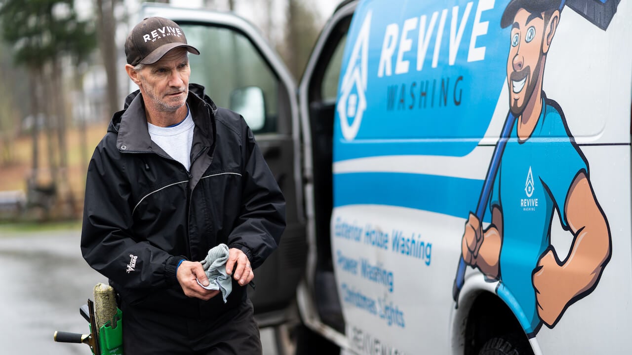 man standing next to a window cleaning company vehicle