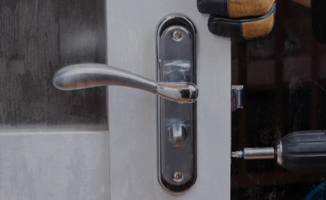 image of a locksmith fixing a door lock after using Jobber's locksmith software
