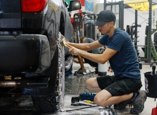 image of auto detailer cleaning the tire and rim of a car
