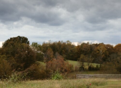 Lanscaper mowing a lawn while storm clouds roll in.
