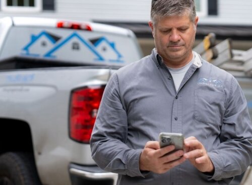Roofing service provider looking down at mobile phone.