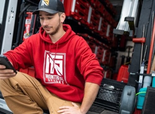 Electrician sitting in the back of work vehicle on his phone