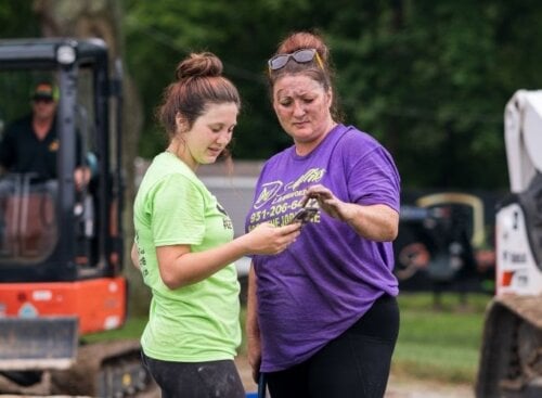 Two lawn care technicians on-site, looking through mobile device