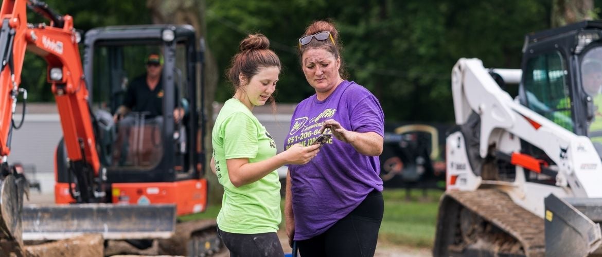 Two lawn care technicians on-site, looking through mobile device
