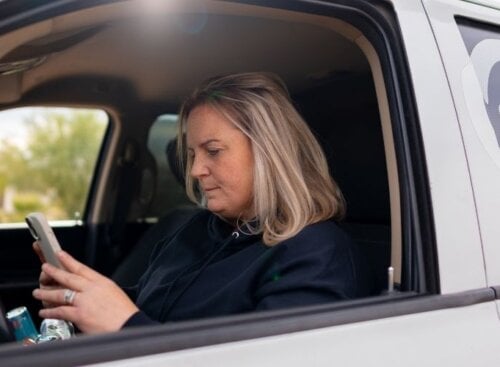 HVAC technician sitting in a work truck while looking at their phone.