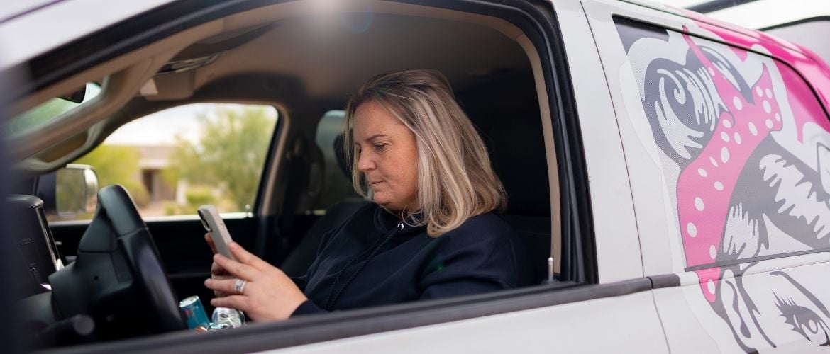 HVAC technician sitting in a work truck while looking at their phone.
